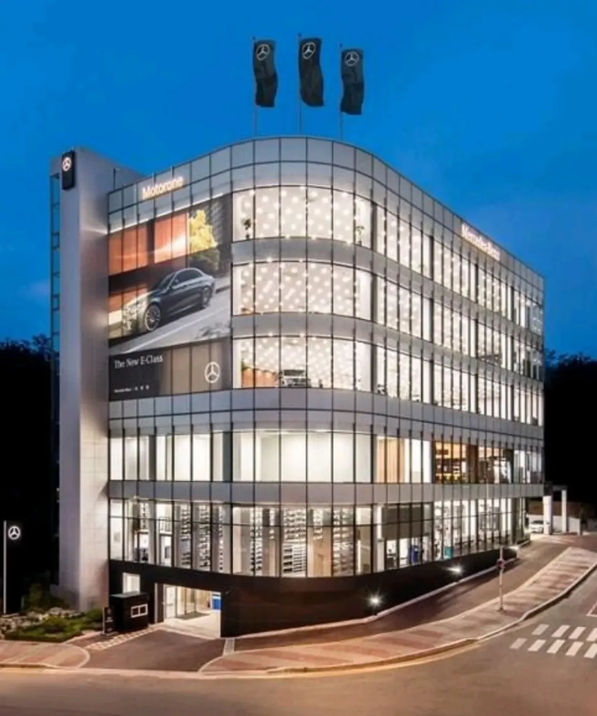 저녁 조명이 켜진 Mercedes-Benz 전시장 건물 외관
