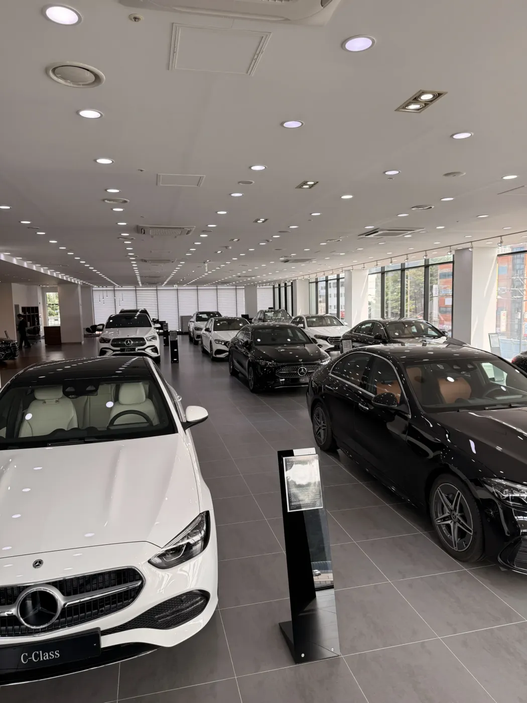 전시장에 여러 대의 Mercedes-Benz 신차가 줄지어 전시된 모습