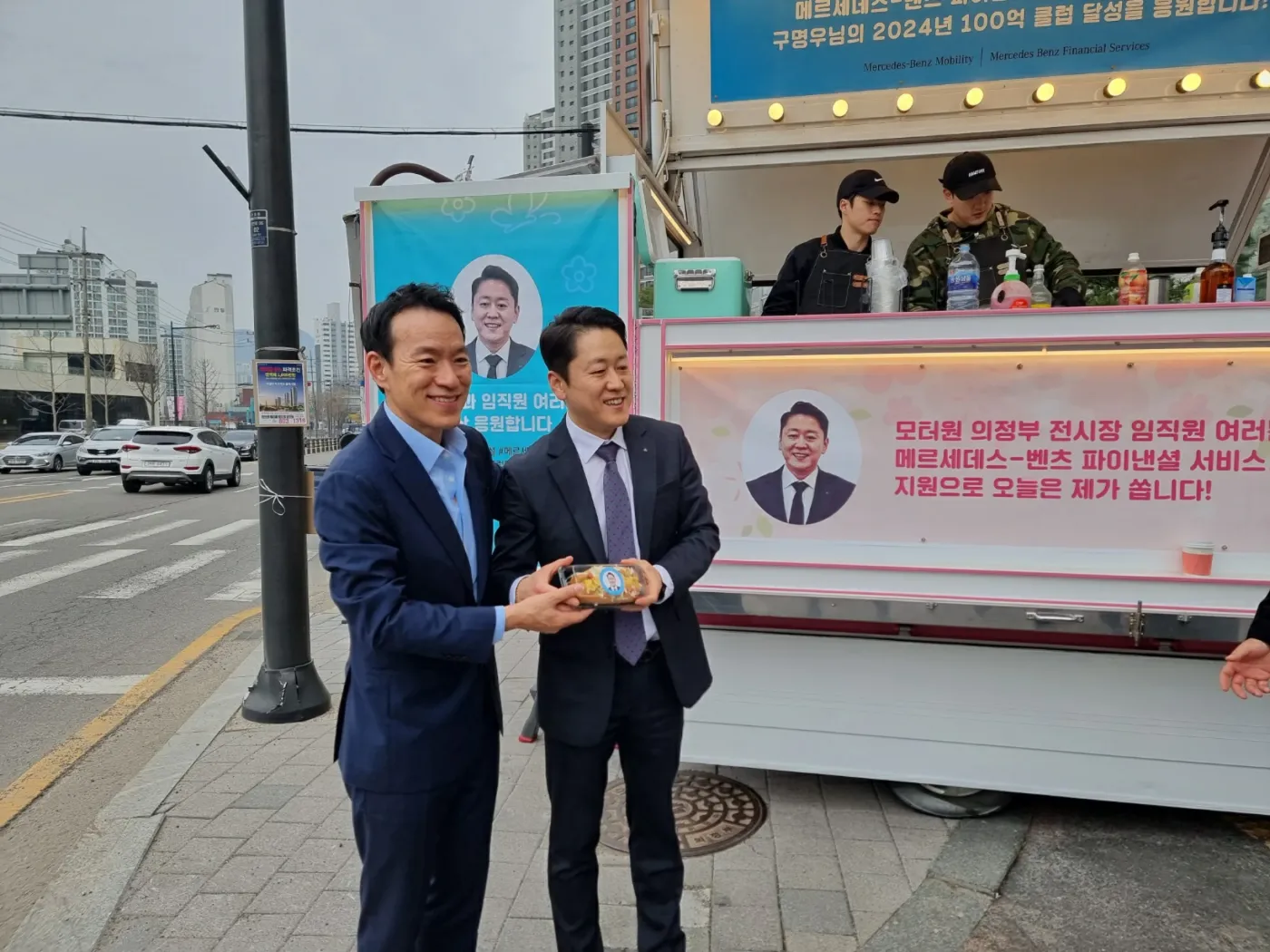 구명우 딜러의 얼굴이 실린 배너가 걸린 커피차 앞 행사 현장